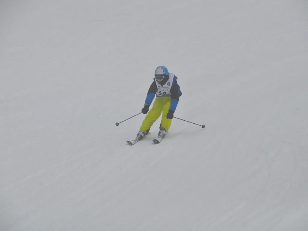 Skifahrer mit gelber Hose auf der Rennstrecke.